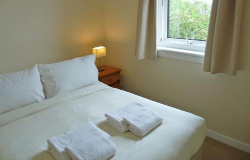 um quarto com uma cama branca com duas toalhas em Ewen's House em Stenscholl