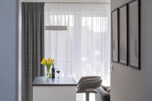 a table with a vase of flowers and a window at Apartament Green Lake - Mrągowo in Mrągowo