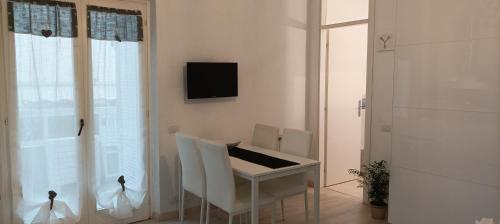 a white table and chairs in a room with a television at La casina di Ale in Marina di Carrara