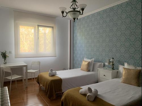a bedroom with two beds and a table and a window at Falda do Pedroso in Santiago de Compostela