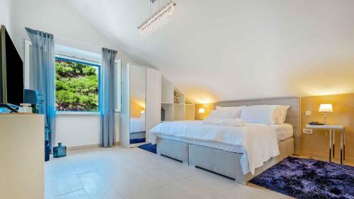 Un dormitorio con una gran cama blanca y una ventana. en A gorgeous villa on a private property on the island Brač, en Pučišća