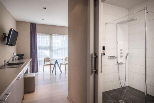 a bathroom with a shower and a sink and a table at C-Hotels Excelsior in Middelkerke