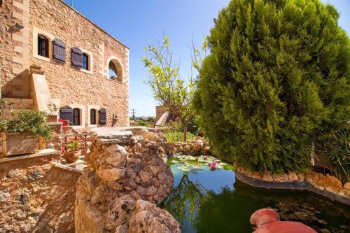 a house with a pond in front of a building at Samonas - 5 maisonettes with breathtaking views in Chania Town