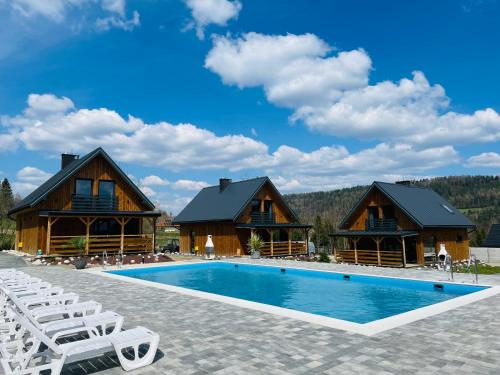 a resort with a pool and two log homes at Na Jasieniu in Ustrzyki Dolne