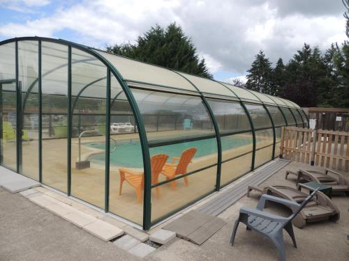 une maison en verre avec deux chaises et une piscine dans l'établissement CHALET ATYPIQUE LOLA type KOTA location en gîte, à Chazemais