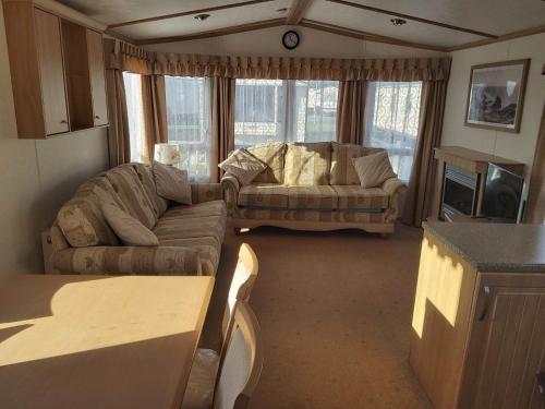 a living room with a couch and a table at 6 BERTH DELUXE CARAVAN PG73 GOLDEN PALM in Chapel Saint Leonards