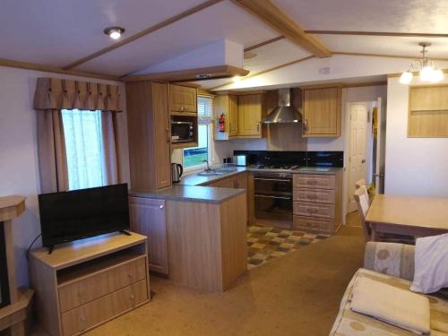 a large kitchen with wooden cabinets and a counter top at 6 BERTH DELUXE CARAVAN PG73 GOLDEN PALM in Chapel Saint Leonards