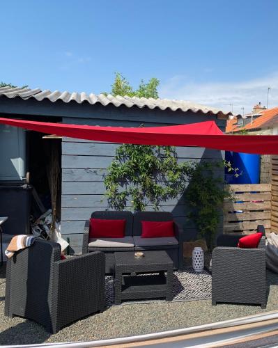 d'une terrasse avec un canapé et des chaises à baldaquin rouge. dans l'établissement JOUANNEAU, au Mans