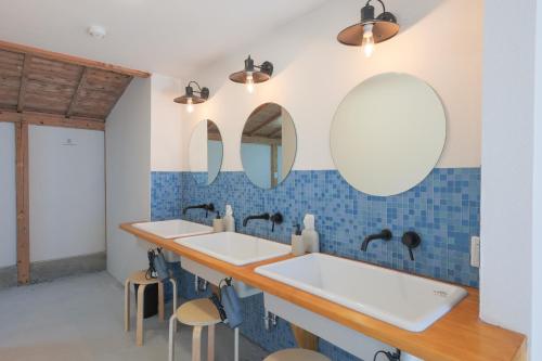 2 lavabos en un baño con espejos y taburetes en guesthouse minkä, en Amami