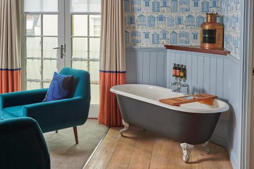 ein Badezimmer mit einer freistehenden Badewanne und einem blauen Stuhl in der Unterkunft Hotel Du Vin Poole in Poole