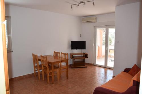 uma sala de estar com uma mesa e cadeiras e uma televisão em Apartment Blanusa B em Povljana