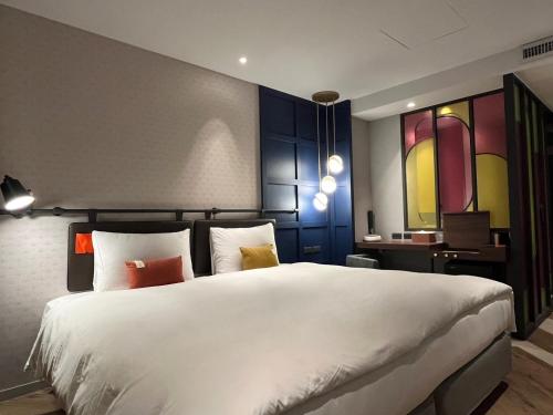 a bedroom with a large white bed and a desk at OLAH Poshtel - Taichung Station in Taichung