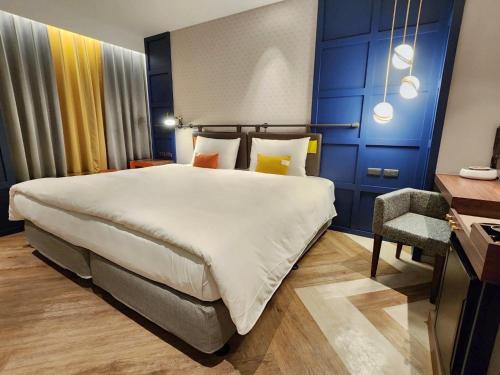 a hotel room with a large bed and a chair at OLAH Poshtel - Taichung Station in Taichung