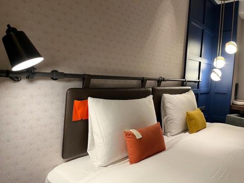 a bedroom with a bed with colorful pillows on it at OLAH Poshtel - Taichung Station in Taichung
