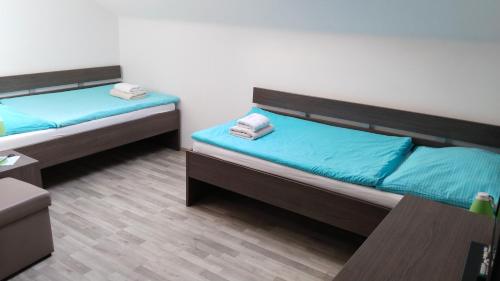two beds in a room with blue sheets at PENZION U BRÁZDŮ in Ivančice