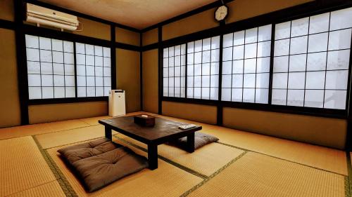 um quarto com uma mesa e um sofá em frente às janelas em 富士吉田たまきや em Fujiyoshida