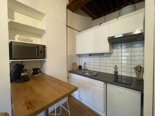 een keuken met witte kasten en een houten aanrecht bij Studio vieille ville in Besançon