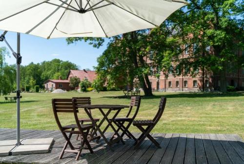 a table and chairs with an umbrella on a deck at Schloss Alt Sammit in Krakow am See