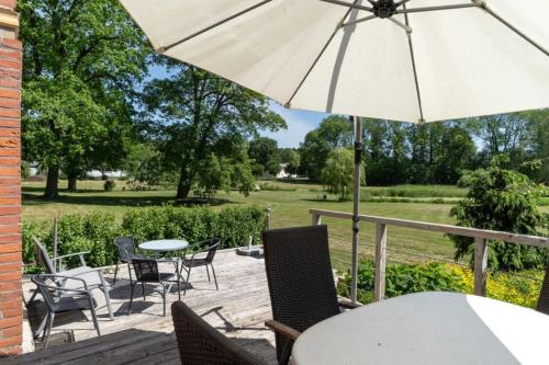 a patio with a table and chairs and an umbrella at Schloss Alt Sammit in Krakow am See