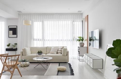 a white living room with a couch and a table at Cosy room with unique interior in Sungai Petani