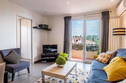 un salon avec un canapé bleu et une télévision dans l'établissement Apt With Balcony With Beach Vue, à Villeneuve-Loubet