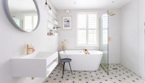 a white bathroom with a tub and a mirror at Cosy room with unique interior in Sungai Petani