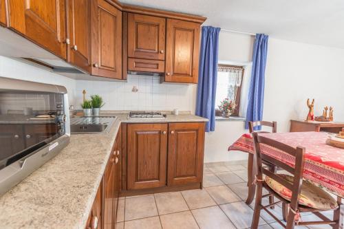 a kitchen with wooden cabinets and a table with a tableablish at L'Atelier du Temps - Clementine Appartements in Cogne