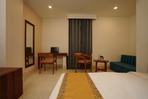 a hotel room with a bed and a couch and a desk at Hotel Royal Palace in Guwahati