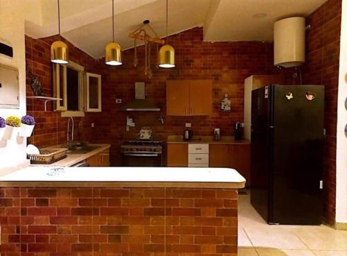 a kitchen with a black refrigerator and a brick wall at Villa amoun in Sidi Kirayr