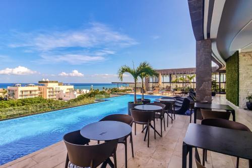 eine Hotelterrasse mit Tischen und Stühlen sowie einem Pool in der Unterkunft Perfect Place 002 in Playa del Carmen