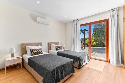 una camera da letto con due letti e una grande finestra di Stunning 5 Bed Villa Calantha with Fantastic Outside Space - Aphrodite Hills a Kouklia