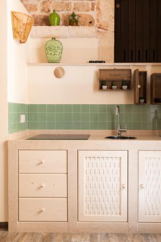 a kitchen with white cabinets and green tiles at Camere Caroseno in Castellana Grotte