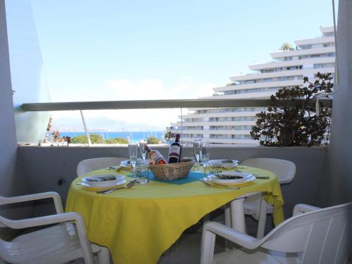 une table avec un chiffon de table jaune sur un balcon dans l'établissement Appartement 3 Pièces, 6 Couchages, Climatisation, Terrasse Vue Mer, Parking - FR-1-252A-55, à Villeneuve-Loubet