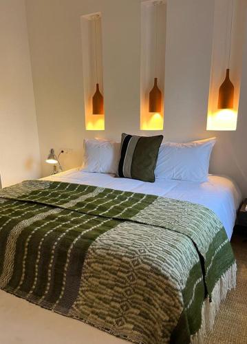 a bedroom with a large bed with a green and white blanket at Manzil La Tortue in Douar Caïd Layadi