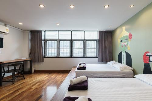 a room with two beds and a desk in it at 99 Hostel Khaosan in Bangkok