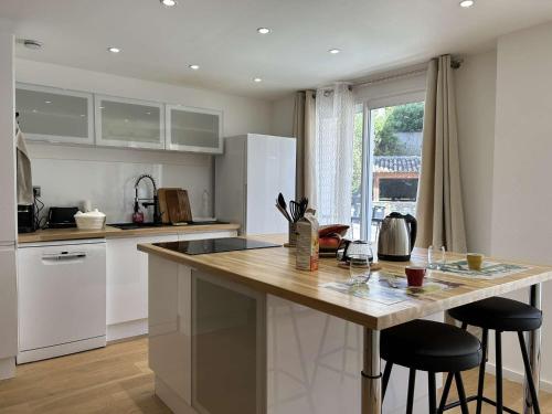 une cuisine avec un comptoir et deux tabourets de bar dans l'établissement Appartement 3 Pièces Climatisé au Cœur de Sainte-Maxime, à 100m des Plages - FR-1-226-513, à Sainte-Maxime