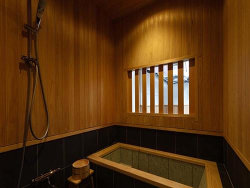 Nipponia Izumo Hirata Cotton Road في إزومو: حوض استحمام في الحمام مع نافذة