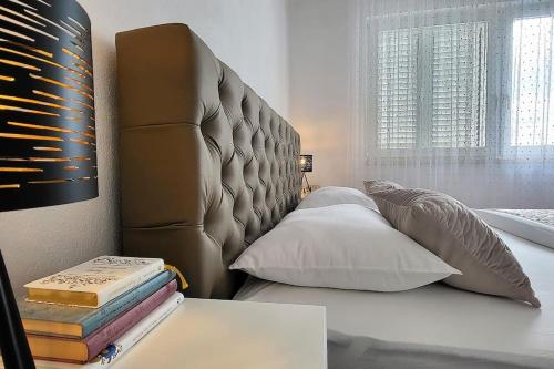 a bed with a headboard and books on a table at SUN apartment with SEA VIEW and shared POOL in Split