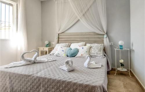 2 Bedroom Awesome Home In Chiclana De La Fronter في شيكلانا دي لا فرونتيرا: غرفة نوم مع مناشف بجعة على سرير