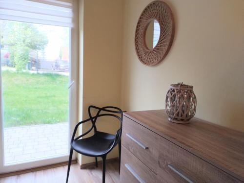 una sedia seduta sopra un comò con uno specchio di Yellow Apartment a Wieliczka