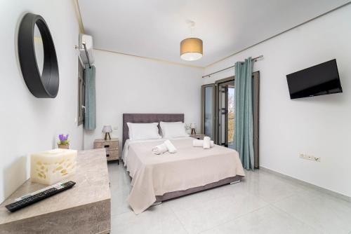 a white bedroom with a bed and a tv at D & G apartment in Kariá