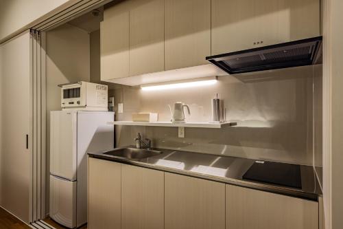 a kitchen with a sink and a white refrigerator at ビル泊 -Birupaku Decentralized Hotel- in Shizuoka