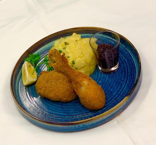 a blue plate with fried food and a glass of juice at Hotel Restaurant Südrast Dreiländereck in Arnoldstein