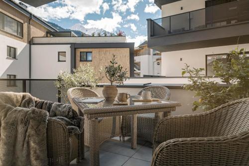 een patio met een tafel en stoelen op een balkon bij monas home mayrhofen in Mayrhofen