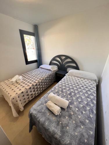 a bedroom with two beds and a table and a window at Corralejo Oasis in Corralejo