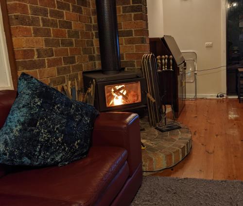 a fireplace in a living room with a couch and a stove at Littlehurst Lodge in Millgrove