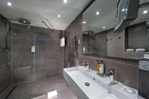 een badkamer met een bad, een wastafel en een spiegel bij Wyndham Stuttgart Airport Messe in Stuttgart