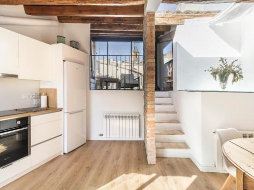 a staircase in a kitchen with white cabinets and a table at Cal Rellotger de Solsona in Solsona