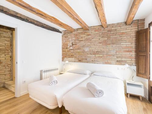 a bedroom with two beds and a brick wall at Cal Rellotger de Solsona in Solsona