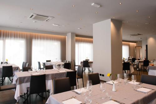 a restaurant with white tables and chairs and windows at Hotel Principe d'Aragona, Sure Hotel Collection by BW in Modica